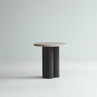 Round marble top table with black cylindrical legs, featuring a sleek modern design and neutral color palette.