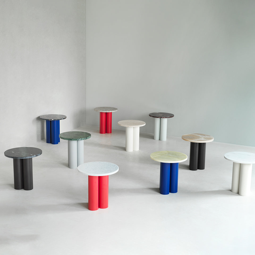 Colorful modern side tables in various shades: red, blue, black, white, and green with unique circular tops and cylindrical bases.