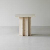 Light beige table with a textured, minimalist design featuring three vertical pillars. Perfect for modern decor.