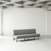Gray minimalist sofa with a sleek fabric finish and simple black legs, set against a light, neutral background.