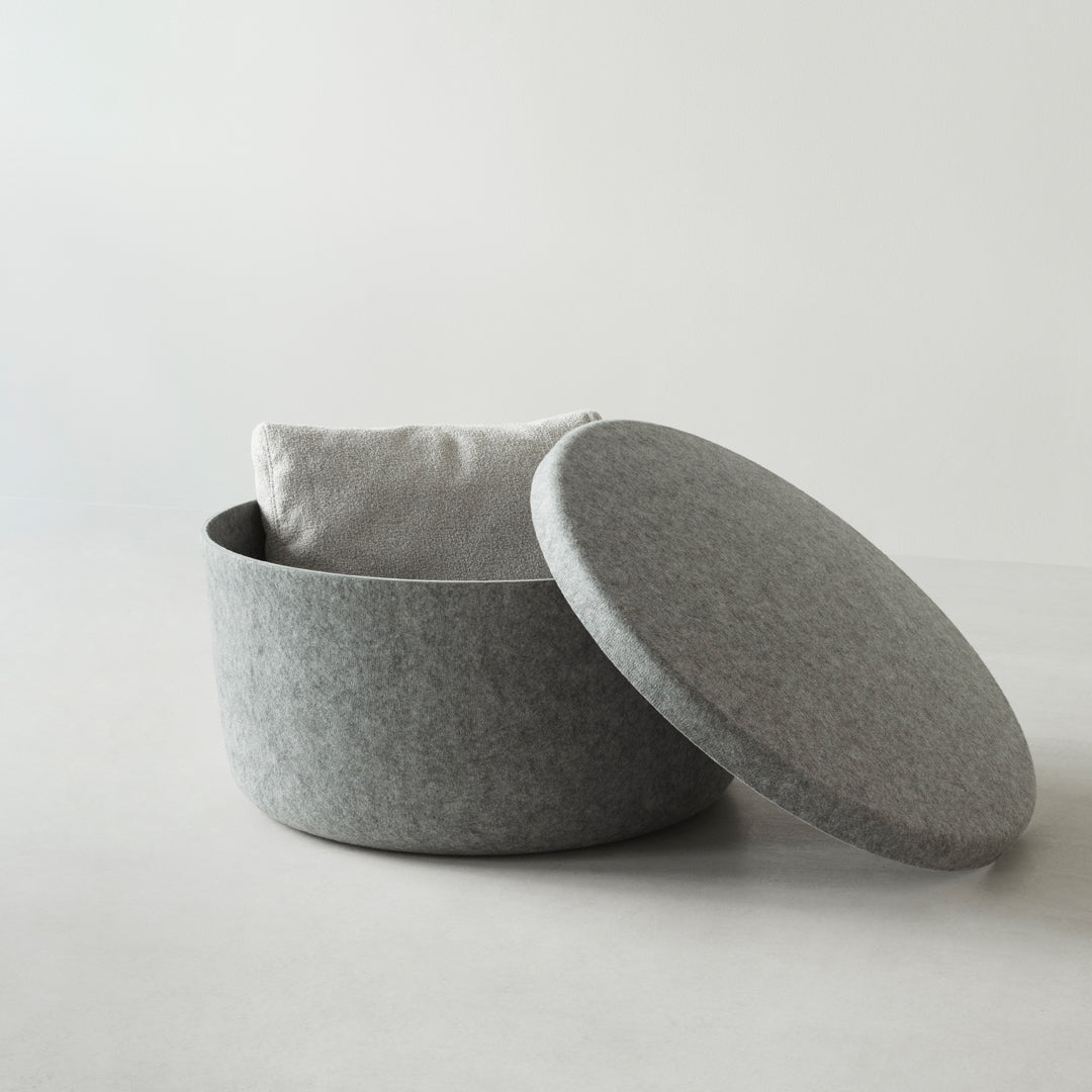 Gray felt decorative storage basket with a smooth rounded lid and a soft white cushion inside. Modern, minimalist design.
