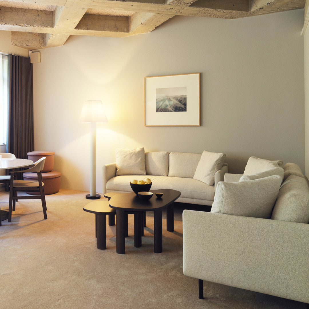 Neutral beige sofa set with white cushions, dark wood tables, and soft gray walls creating a cozy, modern living room ambiance.