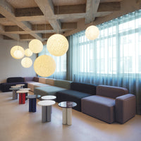 Modern seating in muted tones with geometric shapes and soft patterns; featuring cream, gray, and colorful accent tables.