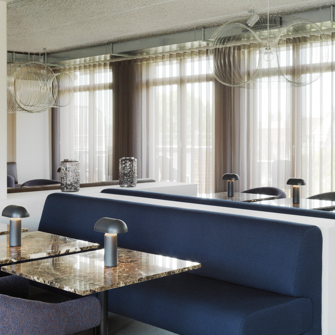 Modern seating in navy blue with white accents, paired with a marble table, complemented by soft curtain patterns.