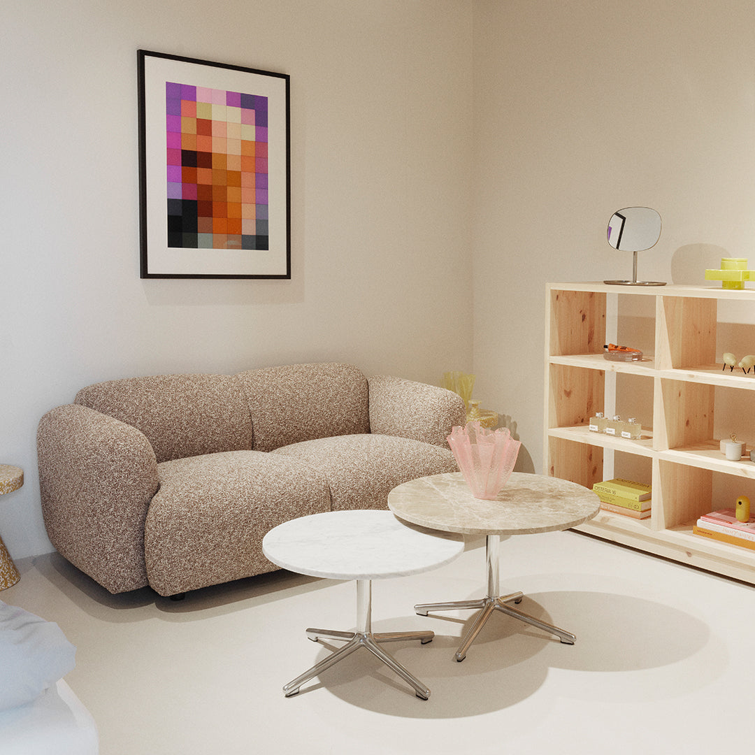Beige textured sofa with light grey and white round tables in a minimalistic room featuring pastel decor.