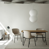 Neutral beige chairs and wooden table under soft, round pendant light, set against a minimalist, light-filled room.