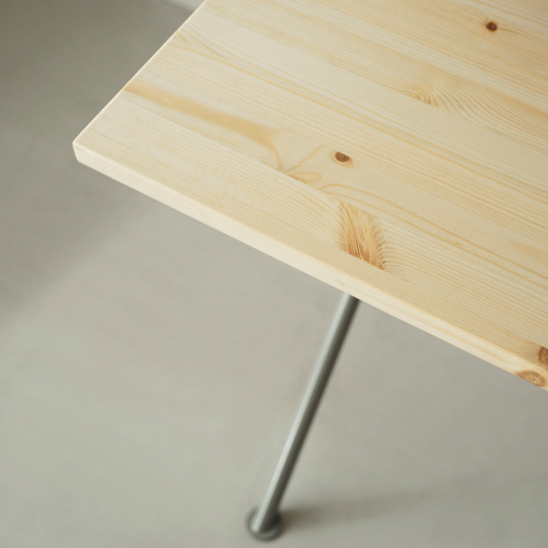 Light natural wood table surface with visible grain pattern, contrasted by sleek metal legs.
