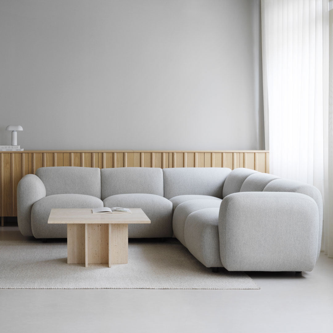 Light gray curved sectional sofa with a minimalist design, complemented by a natural wood coffee table.