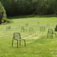 Set of sleek black outdoor chairs arranged on a lush green lawn, showcasing a minimalist design and open pattern.