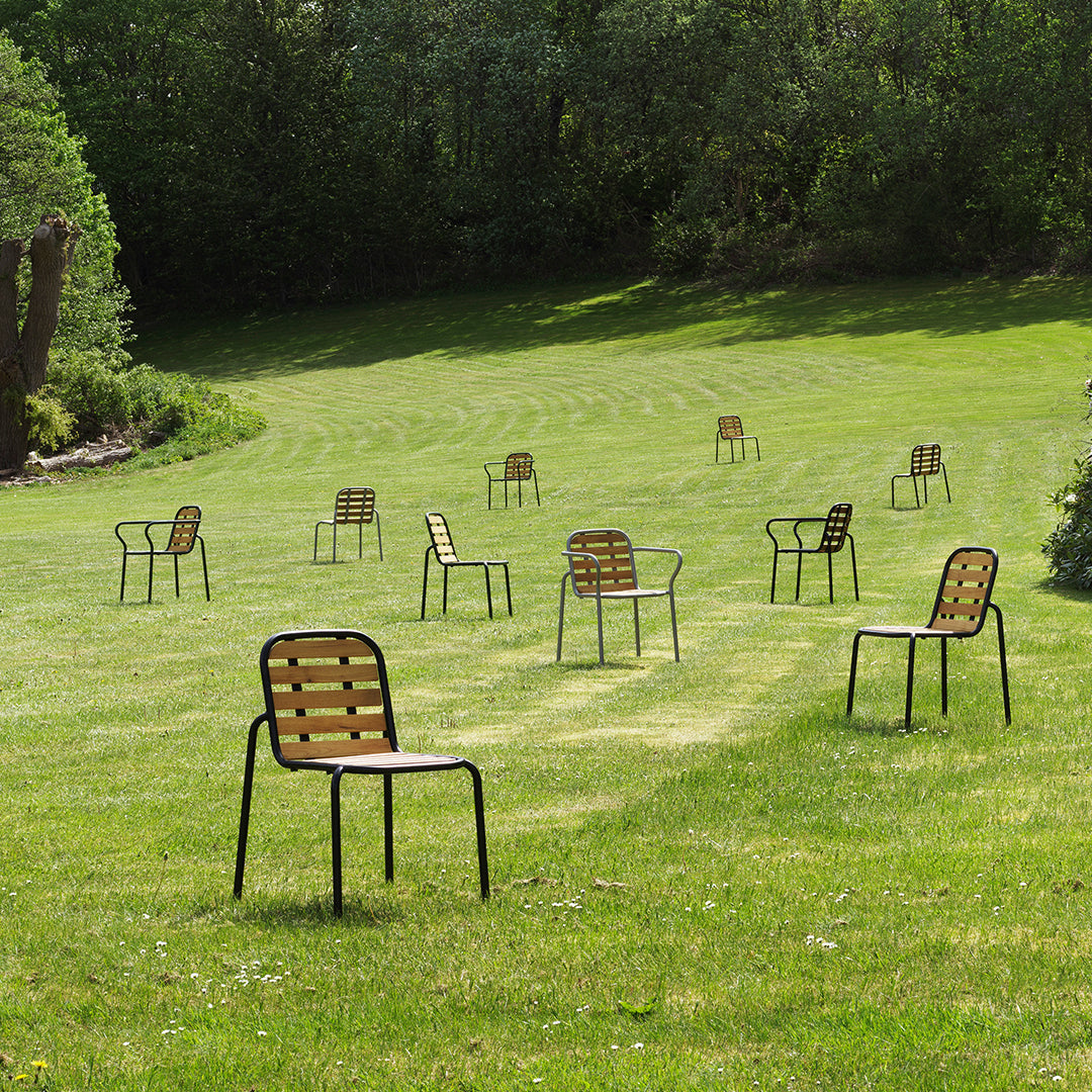 "Collection of outdoor chairs featuring brown striped seats and black metal frames, set against a lush green lawn."