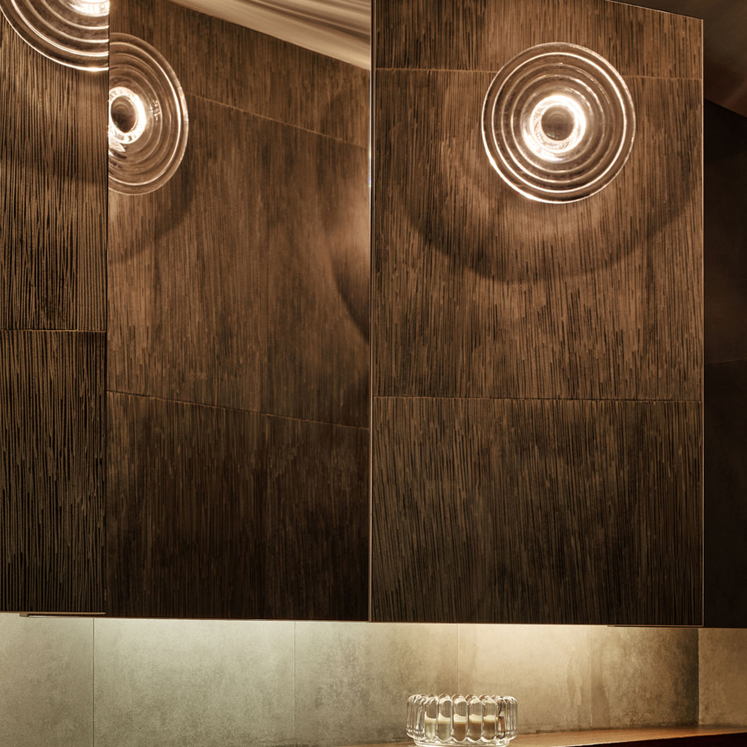 Dark wood paneling with subtle texture and circular light reflections, creating a modern, sophisticated ambiance.