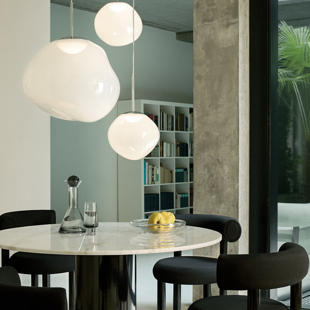 White pendant lights above a round marble table, with sleek black chairs creating a modern, minimalist aesthetic.