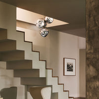 "Modern indoor lighting with silver spherical pendants, set against neutral tones and a textured stone wall."