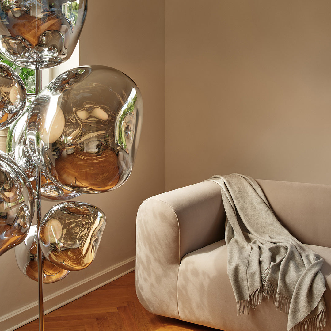 Silver bubble floor lamp next to a beige sofa, featuring soft textures and elegant, neutral tones.