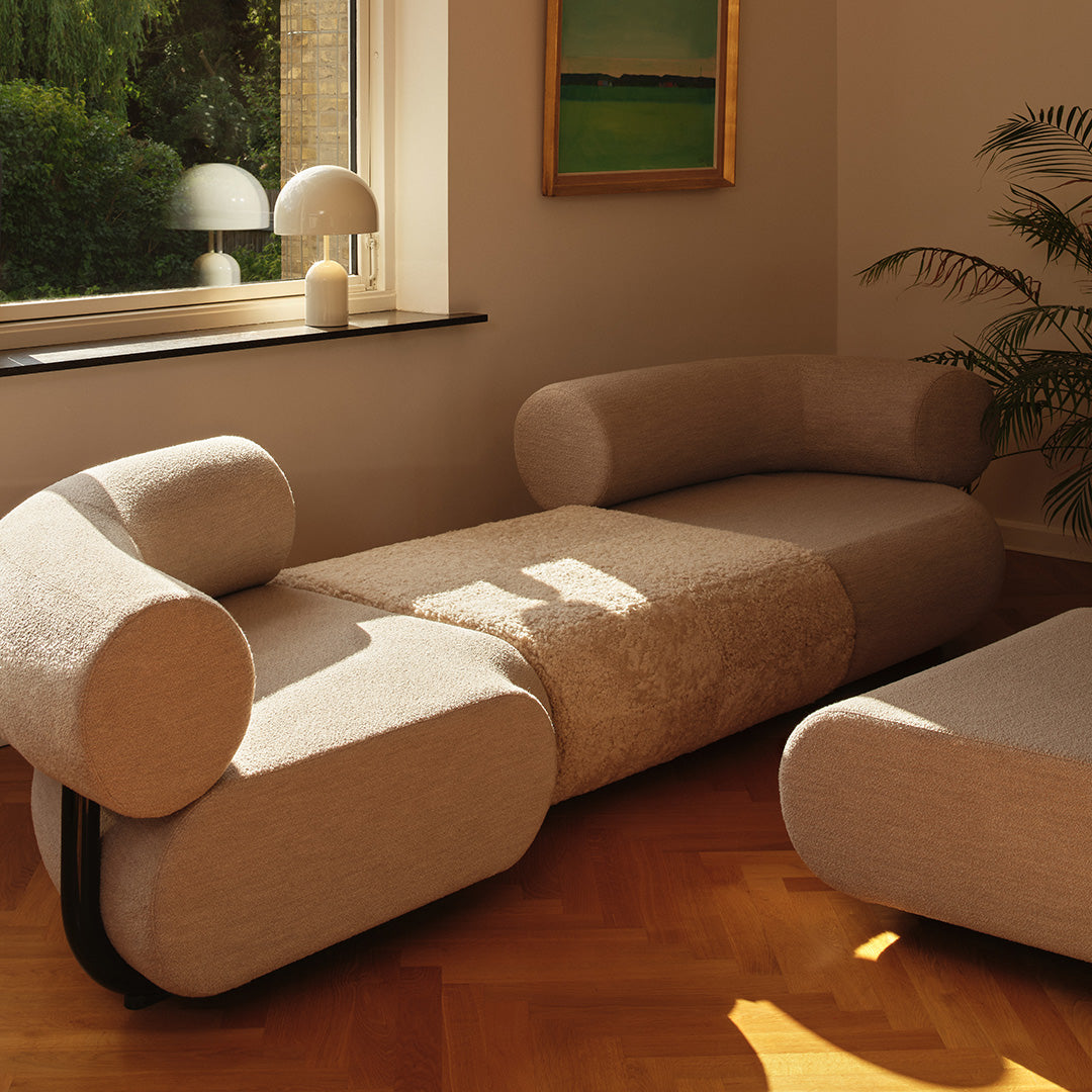 Beige rounded sofa with textured fabric and smooth curves, featuring a contemporary design and cozy aesthetic.