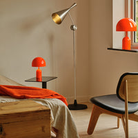 Orange lamps and an orange throw blanket contrast with neutral walls and wooden furniture, creating a warm, stylish ambiance.