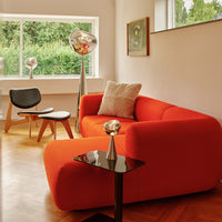 Bright orange modern sofa with a sleek, smooth finish against a neutral-toned room. Ideal for stylish interiors.