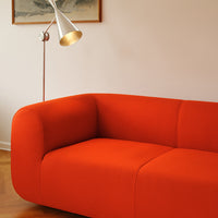 Bright orange modern sofa with smooth, curved lines, perfect for contemporary decor.