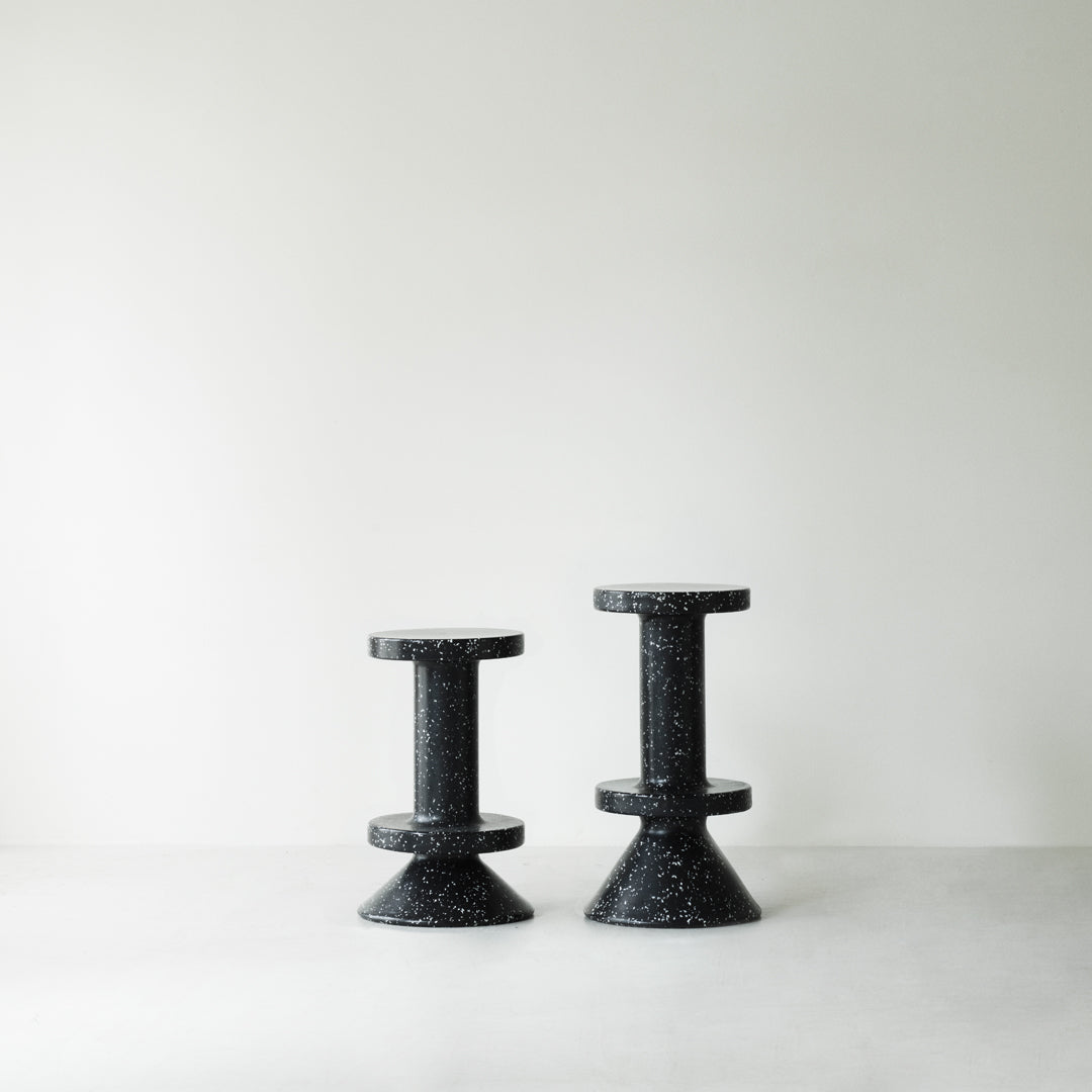 Black speckled cone stools with a modern design, featuring contrasting shapes and textures against a light background.