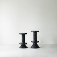 Black speckled cone stools with a modern design, featuring contrasting shapes and textures against a light background.