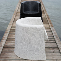 White speckled chair and solid black chair on wooden dock, showcasing modern design and contrasting colors.