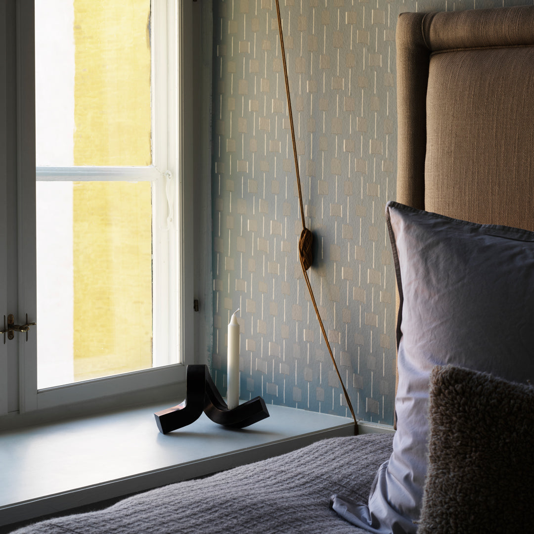 Soft beige headboard with textured cushions, blue patterned wallpaper, and yellow accent wall in a cozy bedroom setting.