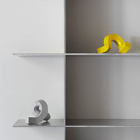 Modern shelf display featuring a gray and yellow abstract sculpture with smooth curves and clean lines.