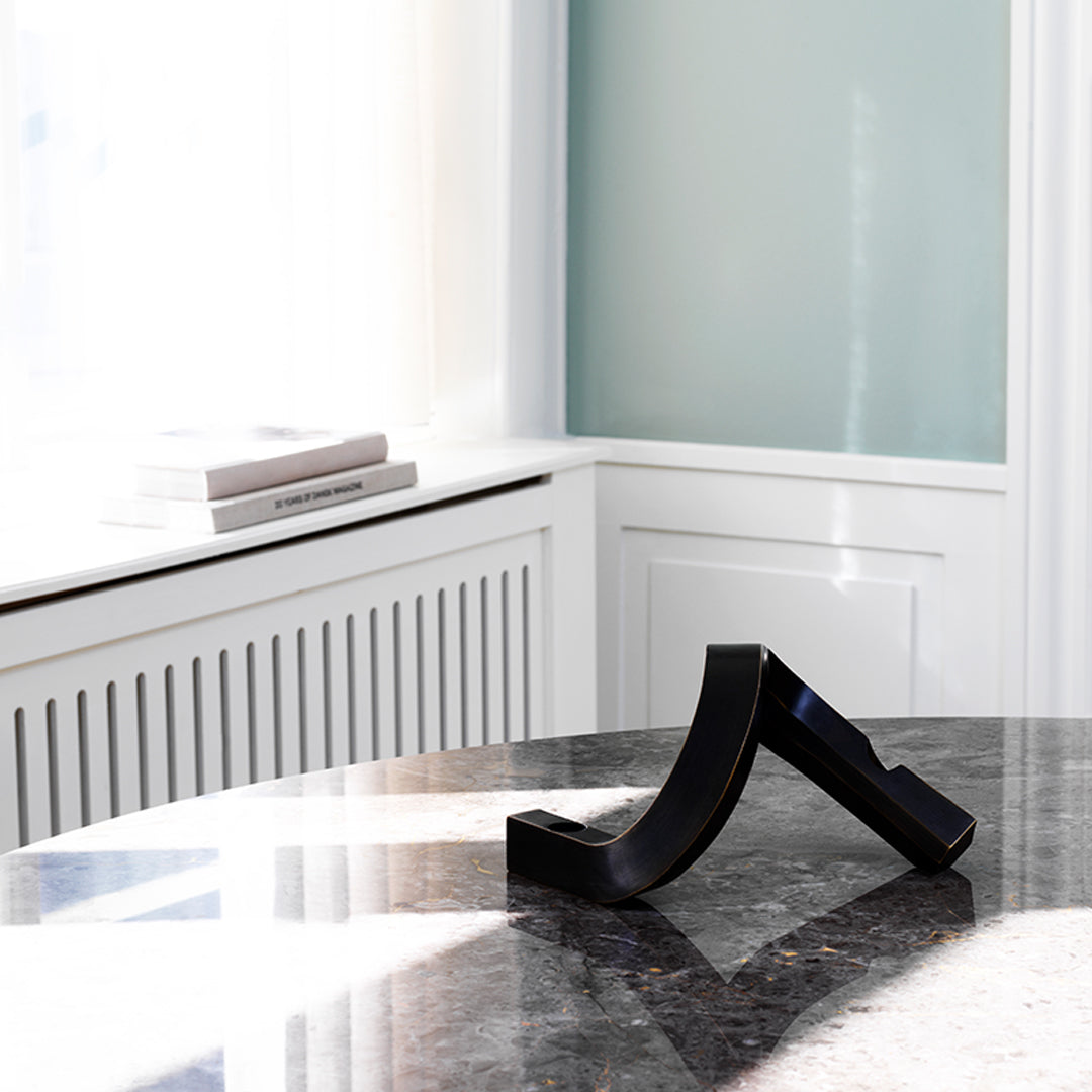 Black curved bookend on a sleek marble surface, featuring modern design against a minimalist background.