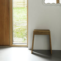 Natural wood stool with a minimalist design, showcasing warm brown tones and a smooth finish against a neutral backdrop.