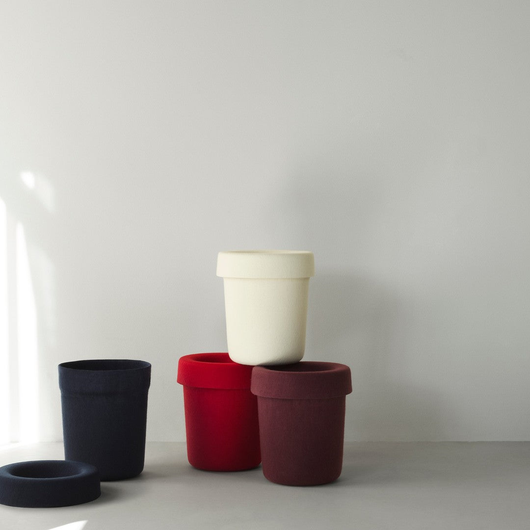 Stack of patterned pots in navy, red, burgundy, and cream against a minimalistic gray background.