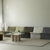 Cozy sofa in muted shades of green, gray, and cream with a quilted pattern, complementing a minimalist living space.