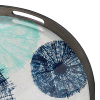 Round tray featuring teal and navy circular patterns on a white background with a dark rim.