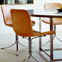 Tan leather chairs with chrome legs around a sleek black marble table, set against a light wooden floor.