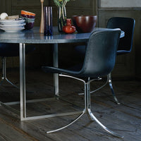"Modern dining set featuring a sleek gray tabletop, black leather chairs, and a mix of colorful vases and bowls."