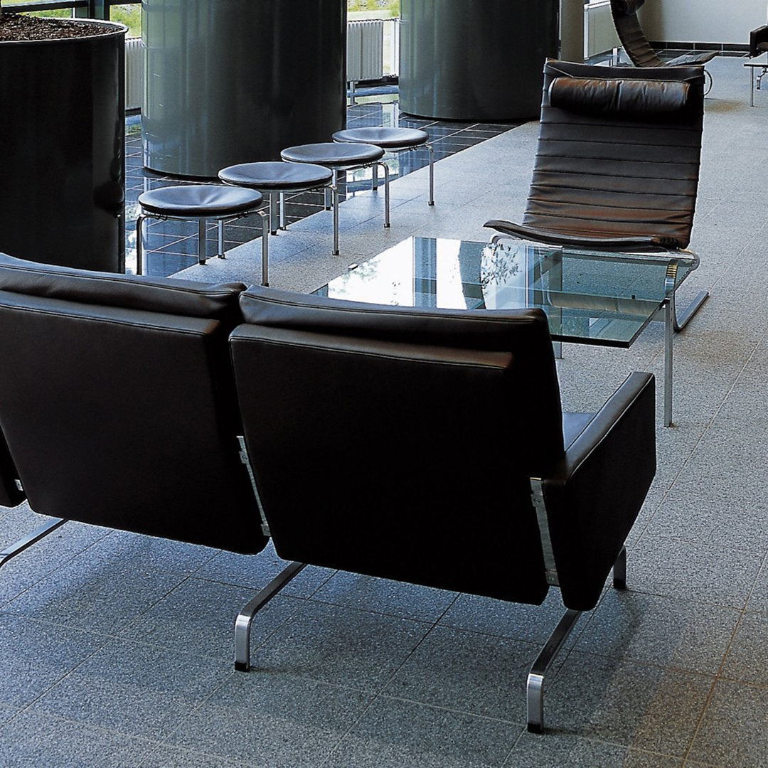 Modern black leather lounge chairs with sleek metal frames, set on a light gray tile floor. Stylish and contemporary design.