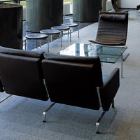 Modern black leather lounge chairs with sleek metal frames, set on a light gray tile floor. Stylish and contemporary design.