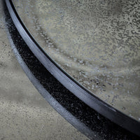 Close-up of a textured metallic surface featuring a black rim, with subtle gray and silver patterns.