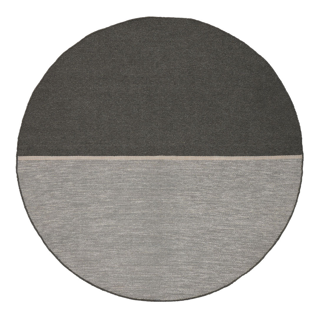 Round area rug featuring a split design in dark gray and light gray, showcasing modern, minimalist patterns.