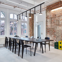 Modern black dining table with sleek lines, paired with black chairs in a minimalist, bright industrial space.