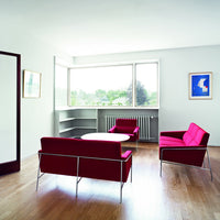 Modern living room with bold pink furniture against light wood flooring and minimalistic decor.