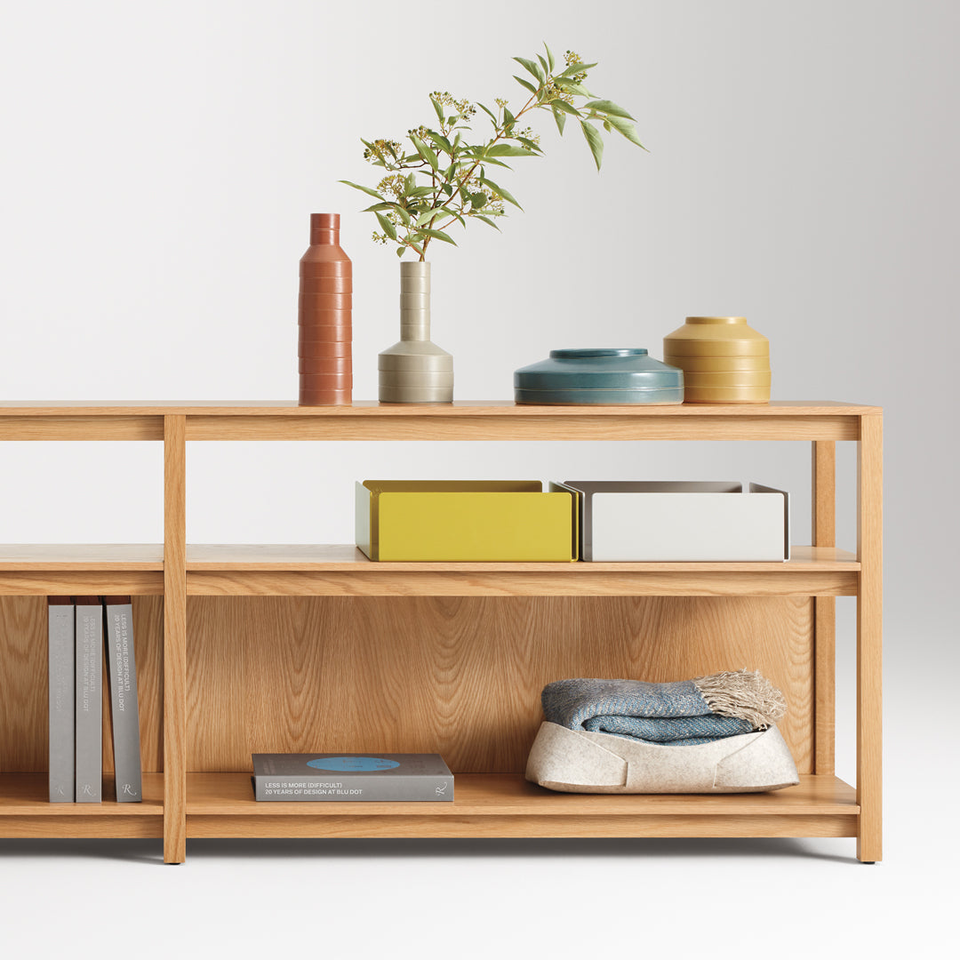 "Light wood shelf featuring vibrant vases and colorful books, showcasing earthy tones and modern patterns."