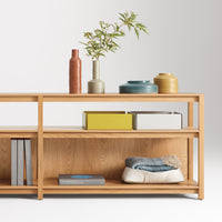 "Light wood shelf featuring vibrant vases and colorful books, showcasing earthy tones and modern patterns."