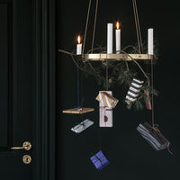 Colorful wrapped gifts in purple, blue, and gold patterns suspended from a modern candle holder against a dark background.