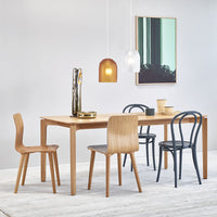 Sleek wooden dining table with natural finish, paired with black and light wood chairs and modern pendant lights.