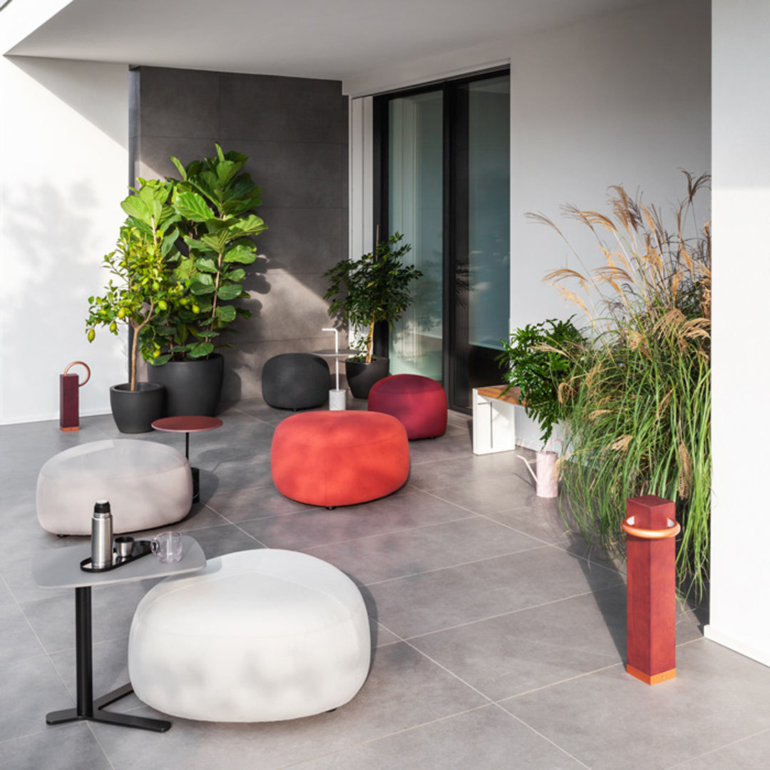 Modern outdoor seating in gray, red, and white with a textured finish, complemented by greenery and stylish decor.