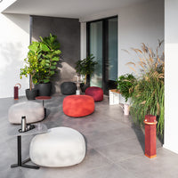 Modern outdoor seating in gray, red, and white with a textured finish, complemented by greenery and stylish decor.
