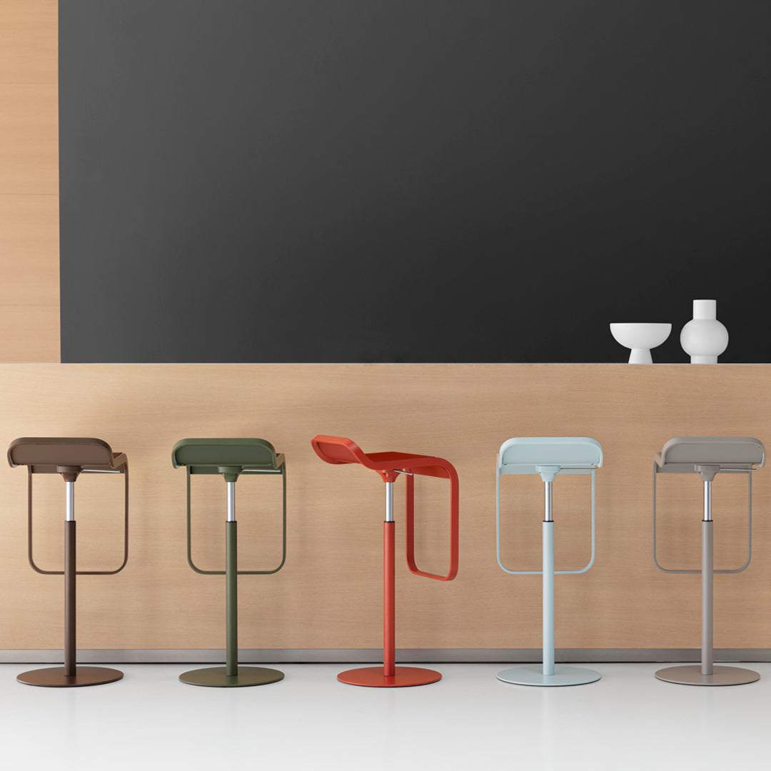 Colorful modern bar stools in olive green, rust red, soft blue, and cool gray against a sleek wooden backdrop.