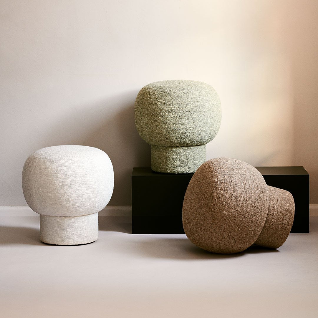 Three decorative stools in white, green, and beige with textured finishes against a neutral backdrop.