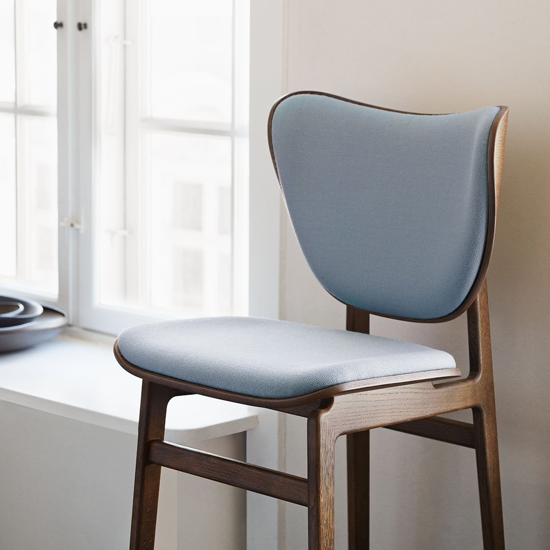 Light blue upholstered chair with a sleek wooden frame, featuring smooth curves and clean lines.