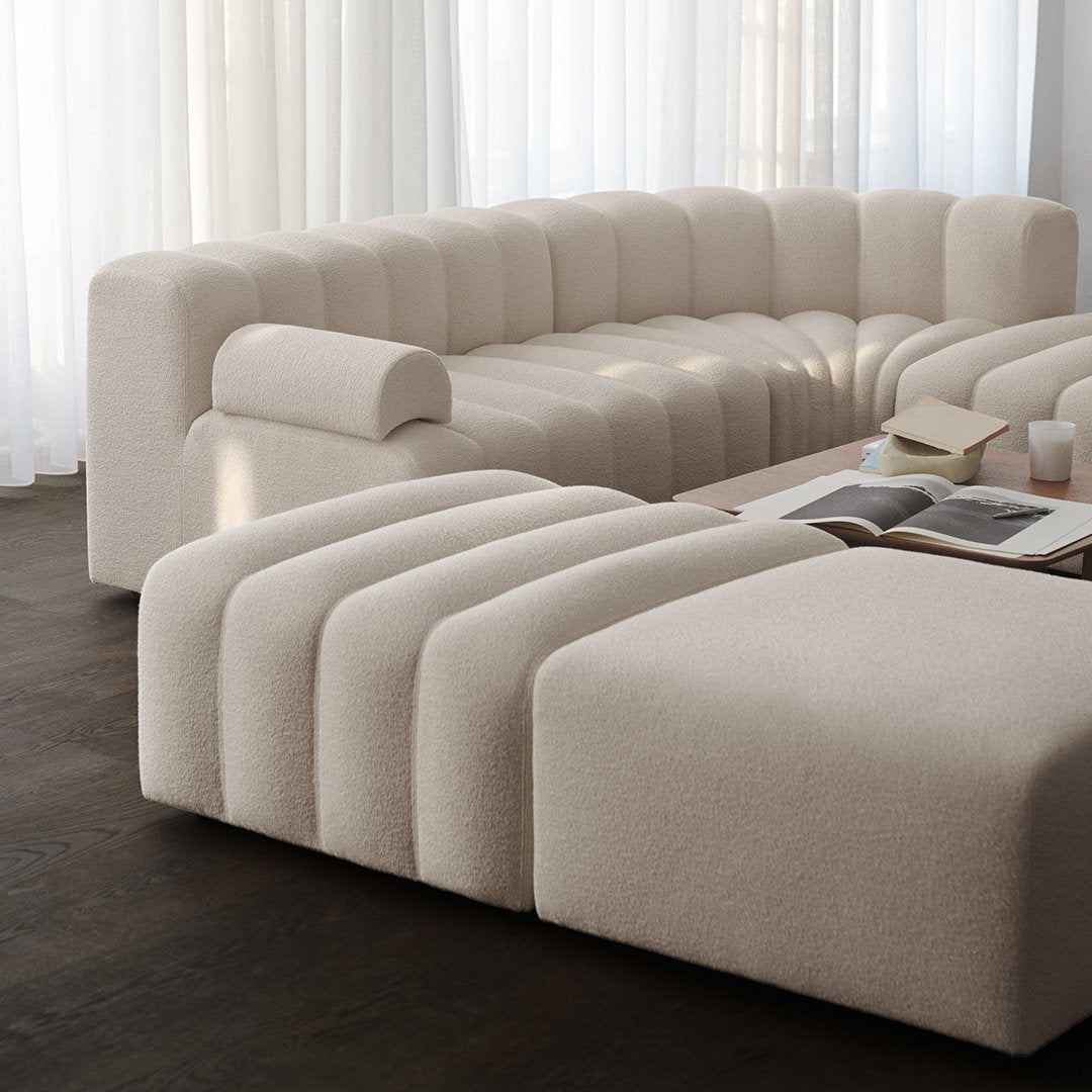 Beige curved sectional sofa with smooth, wavy, textured patterns, complementing a modern aesthetic.
